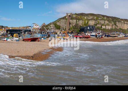 Hastings, East Sussex, UK. 10. März 2019. Hastings Fischerboote hochgezogen hoch auf dem Stade Strand, durch das neue sea Verteidigung und außerhalb der Reichweite der rauen See getrieben von onshore Stürmen geschützt. Hastings hat den größten Strand - Einführung der kommerziellen Fischerei Flotte in Europa. Stockfoto