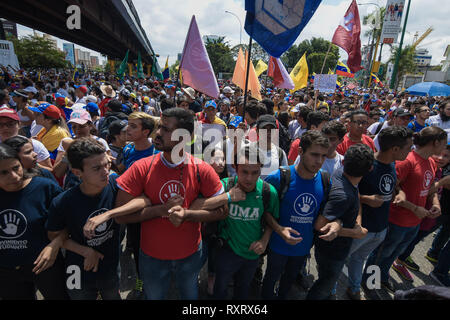 Masse der Demonstranten gesehen halten sie ihre Arme gegenseitig bei einer Anti-government Protests in Caracas. Wut und Frustration, da Tausende von venezolanern die Straßen von Caracas nahm Nationalversammlung leader Juan Guaido zu unterstützen und gegen Präsident Nicolas Maduro Regierung als Caracas verloren die Stromversorgung wieder ein. Stockfoto