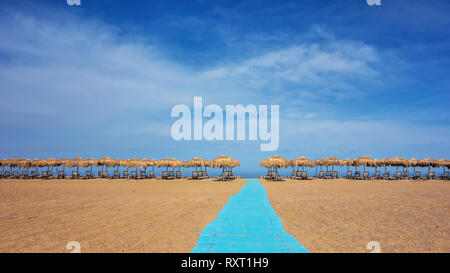 Sonnenschirme und Liegestühle an sonnigen leeren Strand. Griechenland. Kreta Stockfoto