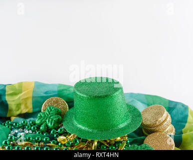 Saint Patrick's Day grün Hut auf einem bunten Schal mit Perlen und Gold Münzen. Weißer Hintergrund. Viel Platz kopieren. Stockfoto