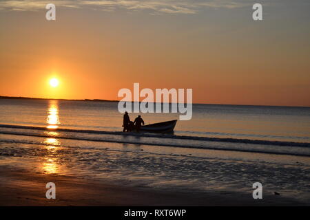 Angeln Boot und 2 Fischer Einstellung aus, als die Sonne über Filey Brigg Yorkshire UK steigt Stockfoto