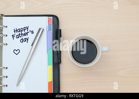 Nahaufnahme einer Tasse Kaffee und Notebook writen Happy Vatertag Stockfoto