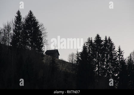 Silhouette eines kleinen Ferienhaus aus Holz auf einem Berghang, der Schwarz-Weiß-Fotografie, monochromatischen alpine Landschaft Stockfoto