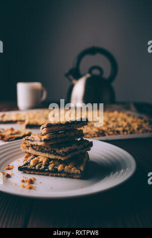 Frisch gebackene Stack von Cookies auf Platte in der Nähe von Kaffee und Teekanne auf rustikalen Hintergrund. Stockfoto