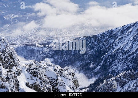 Schneebedeckte zerklüftete Gipfel der Hohen Tatra in der Slowakei mit weit entfernten Gebirgszügen und einer Wolke, die sich über dem Kamm erhebt. Stockfoto