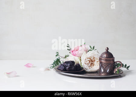 Gruß Ramadan Kareem Karte, Einladung. Mit Datumsangaben Obst, Bronze kaffeetasse, rosa Rosen und grünen Zweigen auf alten Silber Fach weiße Tischplatte Stockfoto