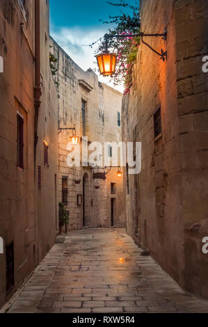 Mdina, Malta: Gasse mit Pflastersteine in der mittelalterlichen Stadt mit Kalksteinwänden und Laternen in den frühen Abend gepflasterte Stockfoto