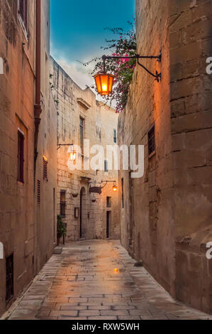 Mdina, Malta: Gasse mit Pflastersteine in der mittelalterlichen Stadt mit Kalksteinwänden und Laternen in den frühen Abend gepflasterte Stockfoto