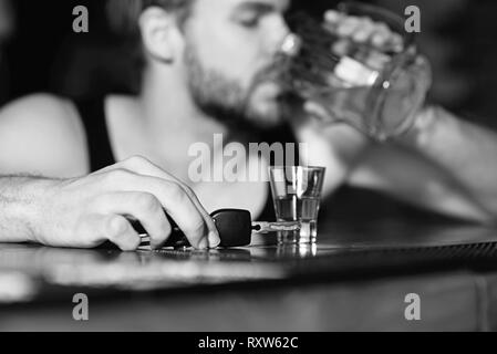 Am Leben bleiben, nicht trinken und fahren. Stattlicher Mann mit Autoschlüssel trinken Bier an der Theke. Mann Trinker im Pub. Alkohol Süchtiger mit Bierkrug. Alkohol Stockfoto