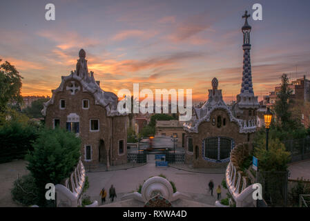 Park Güell Portierloge bei Sonnenaufgang - ein Blick von Gaudis Barcelona, ein internationales Reiseziel in Katalonien, Spanien, in der Dämmerung mit Orange Sky Stockfoto