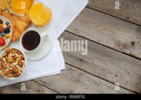 Gesundes Frühstück mit Müsli, Früchte, Beeren, Nüsse, Kaffee, Eier, Honig, Hafer und anderen Nahaufnahme Stockfoto