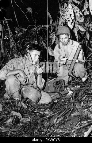 Navajo code talkers Corporal Henry Backen, jr., (links) und Private First Class George Kirk (rechts), mit einem Marine Signal Unit, Betrieb eines tragbaren Radio in einem Clearing sie gerade im dichten Dschungel dicht hinter der Front auf der Insel Bougainville in Papua Neuguinea haben während des Zweiten Weltkrieges im Dezember 1943 gehackt. Stockfoto