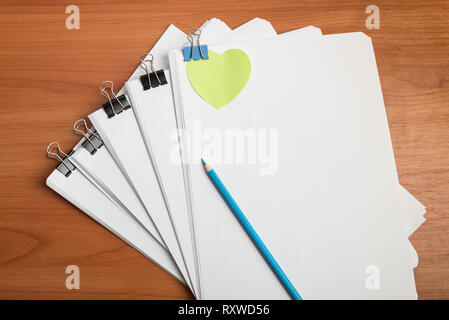 Weißbuch Dokumentenvorlage mit Metallklammern Binder auf der Arbeit Tabelle Ansicht von oben. Grüne Herz Form Aufkleber Stockfoto