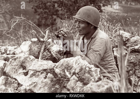 Navajo Indianer code-talker Pfc Carl Gorman in Chinle, Arizona, Manning einen Beobachtungsposten auf einem Hügel mit Blick auf die Stadt von Garapan, während die US-Marines ihre Positionen stärken auf der Insel Saipan, Marianen am 27. Juni 1944 Waren während der Schlacht um Saipan. Stockfoto