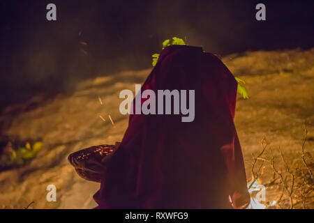 Silhouette der heidnische Priesterin in roter Robe während Ritual durchführen einer Nacht Ritual durch Feuer vor ihr, beleuchtet Stockfoto