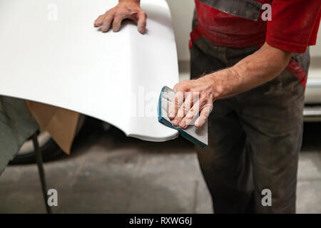 Vorbereitung für die Lackierung eines Autos mit schmirgel schwamm durch einen Servicetechniker, Nivellierung, bevor Sie eine Grundierung nach der Beschädigung auf einen Teil der Stockfoto