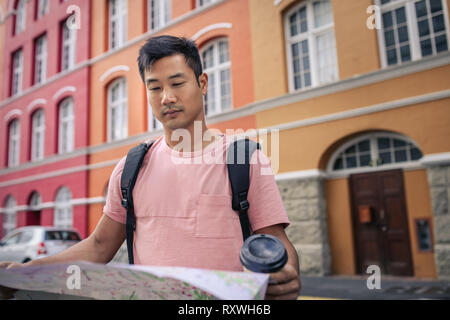 Junge asiatischer Mann Lesen einer Karte, während die Stadt erkunden Stockfoto