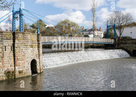 Der viktorianische Eisen Suspension Fußgängerbrücke in den Park über den Fluss Leam mit der Wehr. Stockfoto