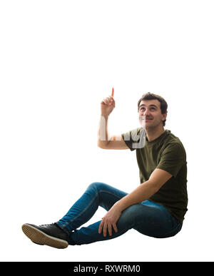 Casual jungen Mann sitzen auf dem Boden zeigen Zeigefinger bis über den Kopf etwas zu zeigen. Happy positive Guy entspannte Stimmung Idee Konzept isoliert Ove Stockfoto