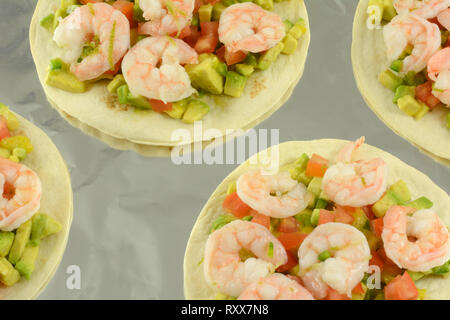 Garnelen tostados mit gehackten Avocado und Tomaten auf Alufolie ausgekleidet Backblech Stockfoto