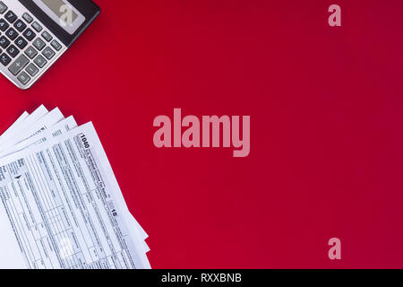 Uns Steuerformular 1040 mit der Anwendung "Rechner" auf rotem Hintergrund. Kopieren Sie Platz. Stockfoto