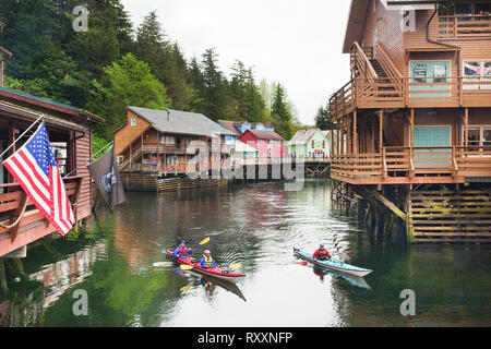 Kayaker paddeln bis Ketchikan Creek der Stadt ehemals 'berüchtigten' Creek Street District, heute ein beliebtes touristisches Gebiet, wo die Geschäfte auf pilings thront inmitten. Ketchikan, Alaska, USA Stockfoto