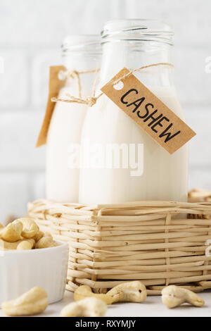 Cashew Milch in der Flasche mit Tag und Rohstoffe. Hellen Hintergrund. Stockfoto