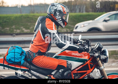 Moskau Russland - 05.März 2018. Motorradfahrer in einem schönen roten Schutzanzug auf einem roten Ducati Motorrad Fahrten entlang in Richtung der Stadt Moskau Stockfoto