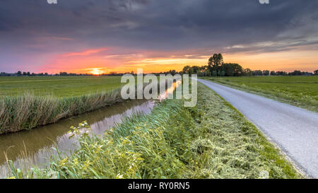 Weitwinkelaufnahme der Landschaft über den Fluss bei Sonnenuntergang in flachen landwirtschaftliche Landschaft in der Provinz Groningen in den Niederlanden Stockfoto