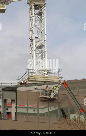 London, Großbritannien - 09 April 2010: Zwei Arbeiter in der Hubarbeitsbühne an Gebäude Baustelle in Londoun, UK. Stockfoto