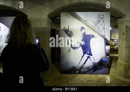 Ein Besucher gesehen zu Fuß durch Banksys Dismaland und andere Ausstellung in Alfandega Congress Center. Die Ausstellung umfasst Bilder aufgenommen von Barry Cawston aus dem Projekt Dismaland (2015), der bekannte Freizeitpark erstellt von Banksy, andere Werke der Künstler als "Walled aus Hotel" (2017) oder "Blume Werfer" (2005), eines seiner bekanntesten Werke integrieren. Abgesehen von Barry Bilder, die Ausstellung lässt sich auch eine Reihe von Werken junger portugiesischer Künstler, auch als Sprungbrett für neue Namen in der Welt der Urban Art. Stockfoto