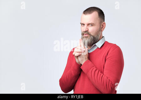 Portrait von glücklich aussehenden bärtigen Mann sagt, ich habe es getan vorgibt, er ist die Waffe in der Hand Stockfoto