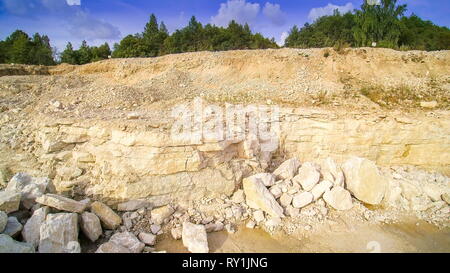 Der Blick auf den Wald neben dem Steinbruch. Es gibt viele grüne Bäume im Wald mit der kalksteinbruch im unteren Teil Stockfoto