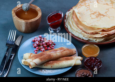 Pfannkuchen mit Beeren, Marmelade, Honig und Schokolade, bestreut mit Puderzucker und Zimt Stockfoto