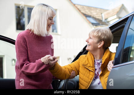 Weibliche Nachbarn geben Senior Woman A Lift im Auto Stockfoto