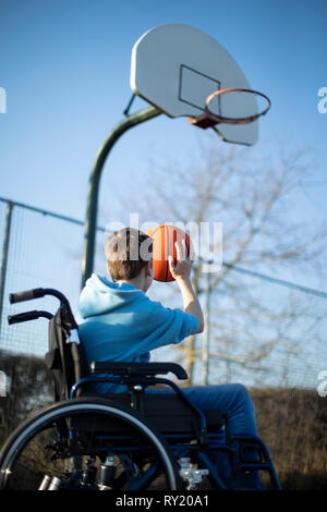 Teenager im Rollstuhl Basketball Shooting Hoop Stockfoto