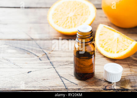 Ätherisches Orangenöl in Flasche, frisches Obst Slices auf Holz- Hintergrund. Natürliche Düfte Stockfoto