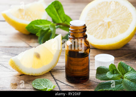 Wesentliche Zitronenöl in Flasche, frisches Obst Slices auf Holz- Hintergrund. Natürliche Düfte Stockfoto