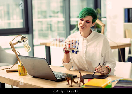 Positive fröhliche junge Frau trinkt leckeren Kaffee Stockfoto