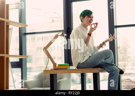 Positive grünhaarige Frau am Telefon Stockfoto