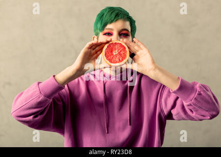 Positive fröhliche Frau, die eine Halbe Grapefruit Stockfoto