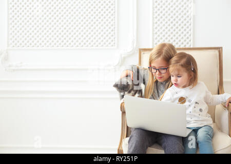 Zwei adorable litle Schwestern mit ihren Computer Laptop zusammen mit ihren Kitten Stockfoto