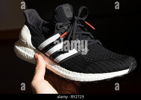 Person, die einen schwarzen Adidas Laufschuh Ultraboost Stockfoto