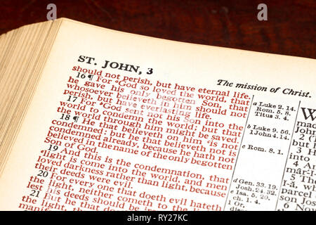 Horizontale Nahaufnahme einer aufgeschlagenen Bibel, Johannes 3:16 in rot gedruckt. Stockfoto