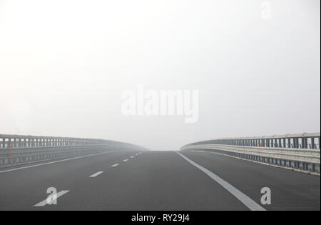 Autobahn mit sehr dichten Nebel gefährlich ohne Autos, während im Winter Stockfoto