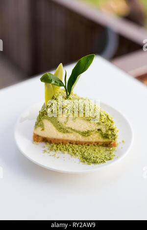 Frisch zubereitete asiatische Matcha Grüntee Käsekuchen mit geriebener Schokolade und Tee Blatt serviert. Traditionelle thailändische Spezialitäten aus frischen Zutaten. Stockfoto