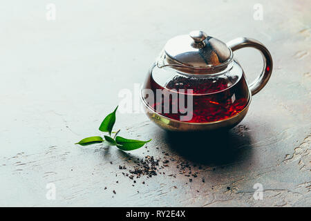 Glas transparent Teekanne und zwei Glas Tassen mit schwarzem Kaffee auf einem dunklen Tabelle Stockfoto