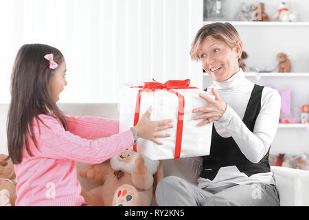 Mutter und Tochter mit Geschenkbox sitzen auf der Couch. Das Konzept der Überraschung Stockfoto