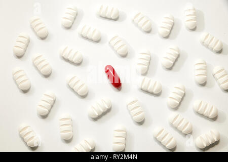 Viele weiße Pillen ein rotes auf weißem Hintergrund Stockfoto