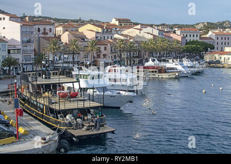 ISOLA LA MADDALENA, Sardinien, Italien - 7. MÄRZ 2019: kleine Fähre Hafen und Palmen gesäumten Strandpromenade Gebäude am 7. März 2019 in Isola La Maddalena, Sardinien, ICH Stockfoto